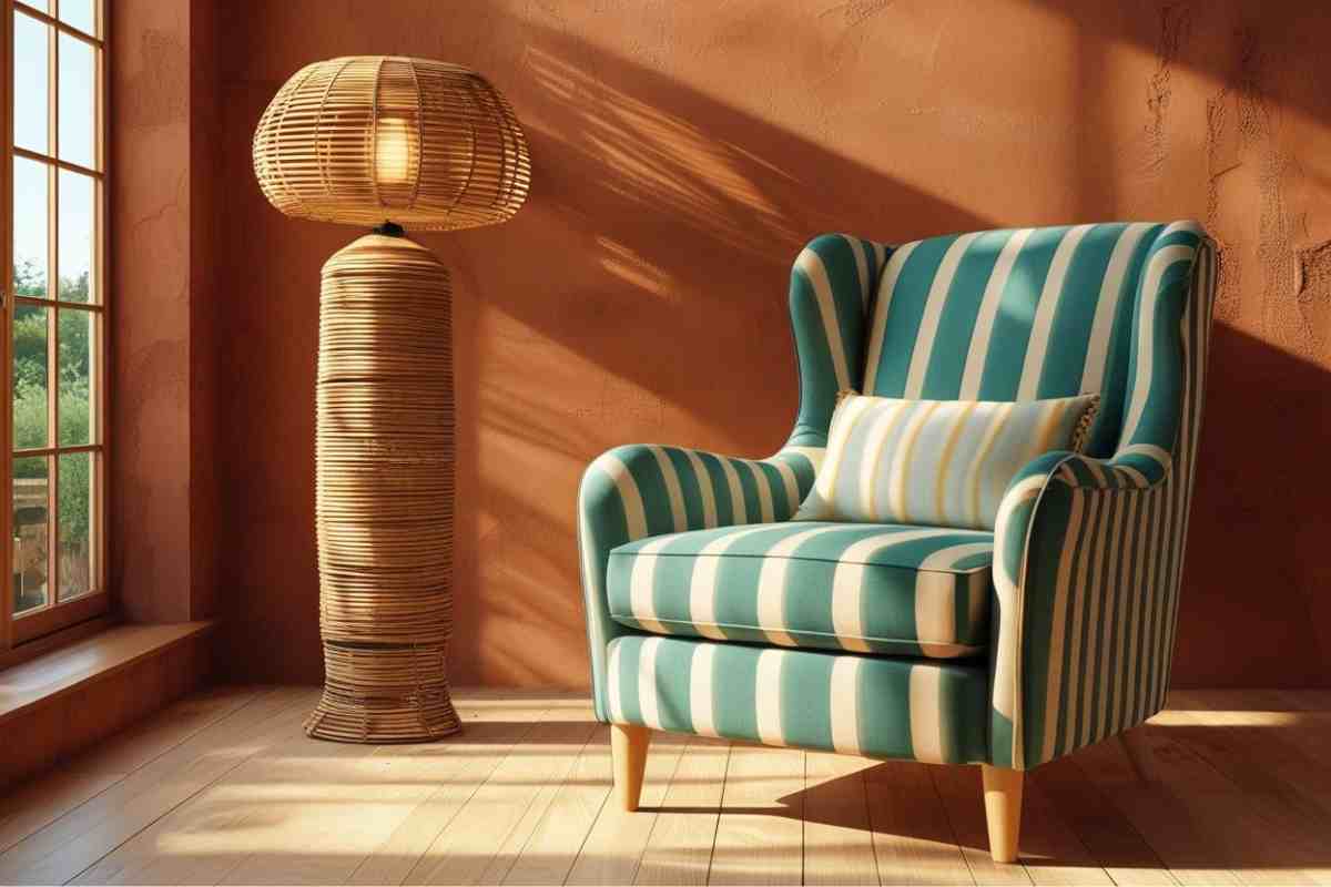 poltrona a righe davanti a finestra con lampada in rattan e parete terracotta