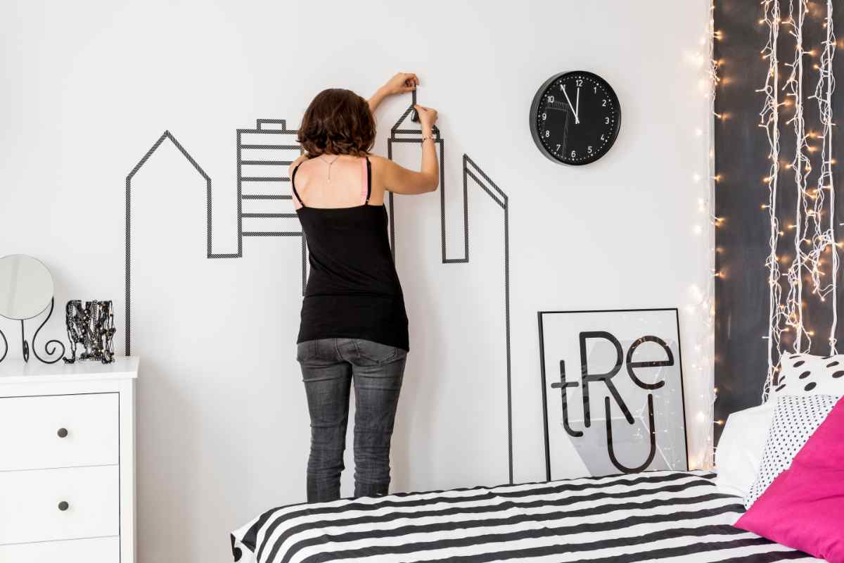 ragazza decora la parete con degli adesivi murali stilizzati per far sembrare più grande la casa piccola