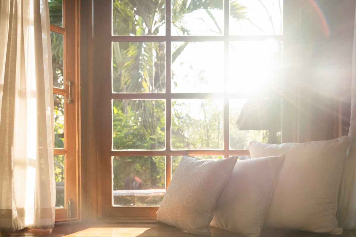 Finestra Bovindo dalla quale entra un raggio di sole arredata con cuscini