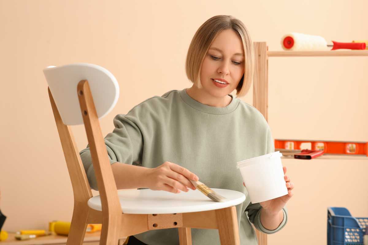 donna alle prese con la stesura del colore sulle sedie dipinte in soggiorno