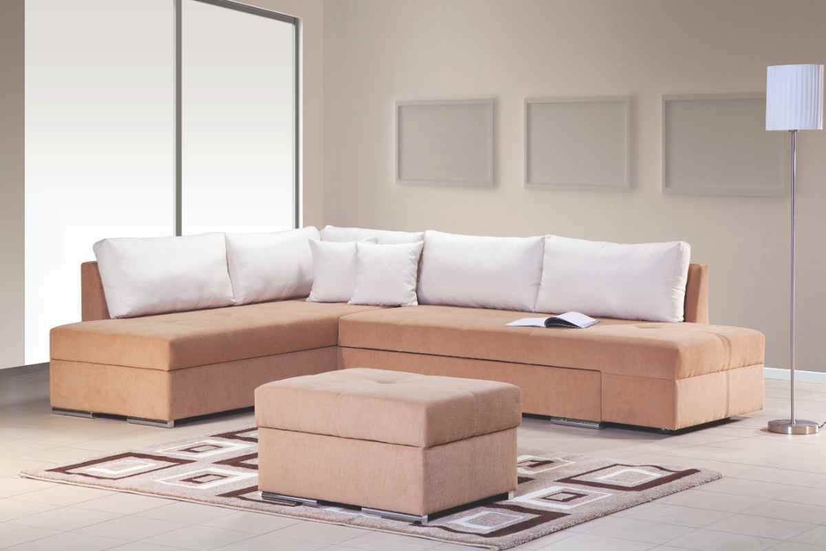 un soggiorno moderno con divano angolare a L e pouf centrale su un tappeto con fantasia geometrica