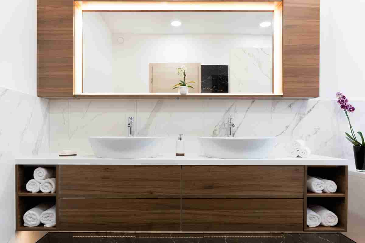 bagno arredato con ampio specchio rettangolare sopra zona lavabo a due vasche