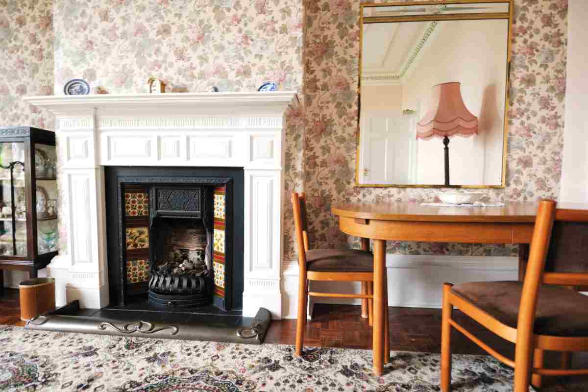 soggiorno con tavolo e sedie in legno con camino e carta da parati floreale in stile country inglese