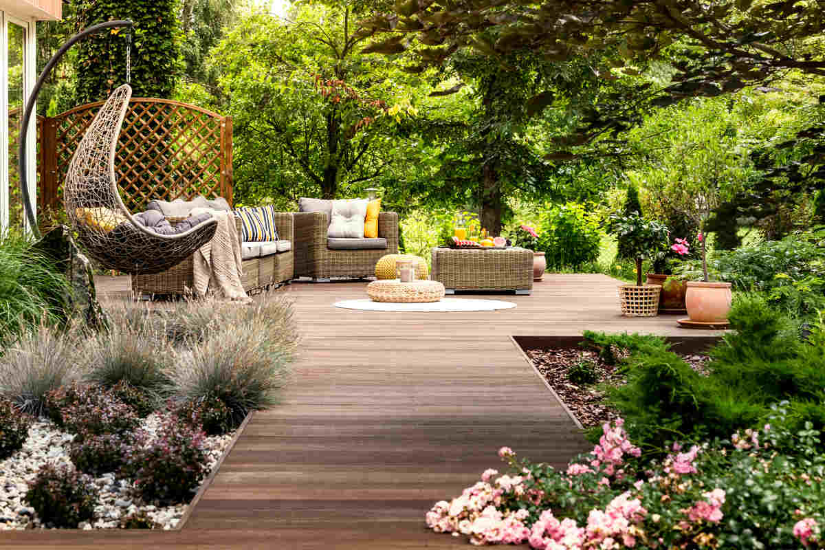 giardino con pavimento in legno con mobili da giardino tra piante e fiori