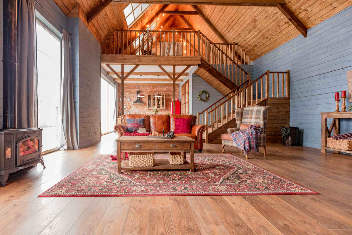 ampio soggiorno con soffitto in legno, parquet, tappeto con divani e tavolinetto e camino moderno