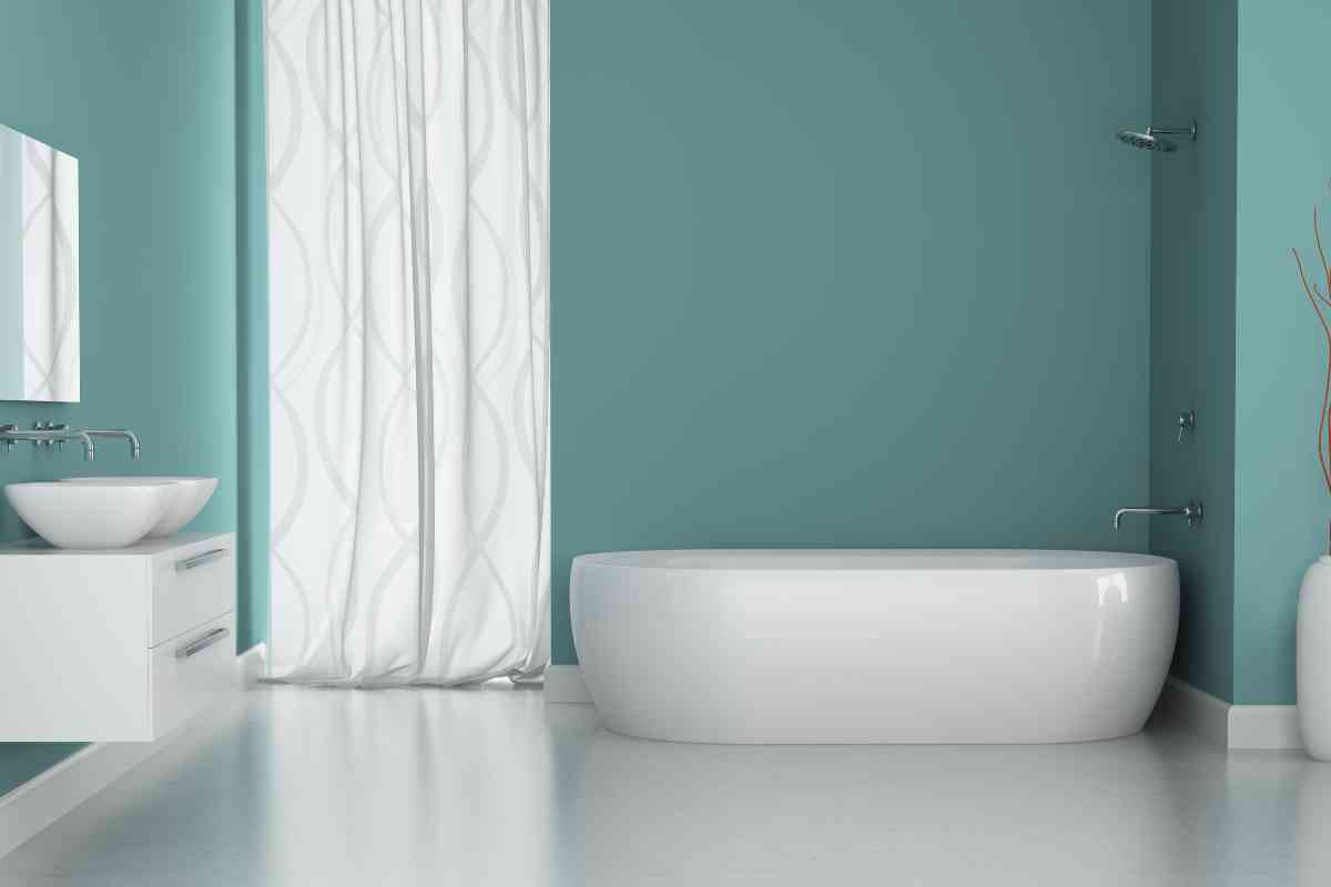 bagno con parete color turchese e sanitari e mobili bianchi