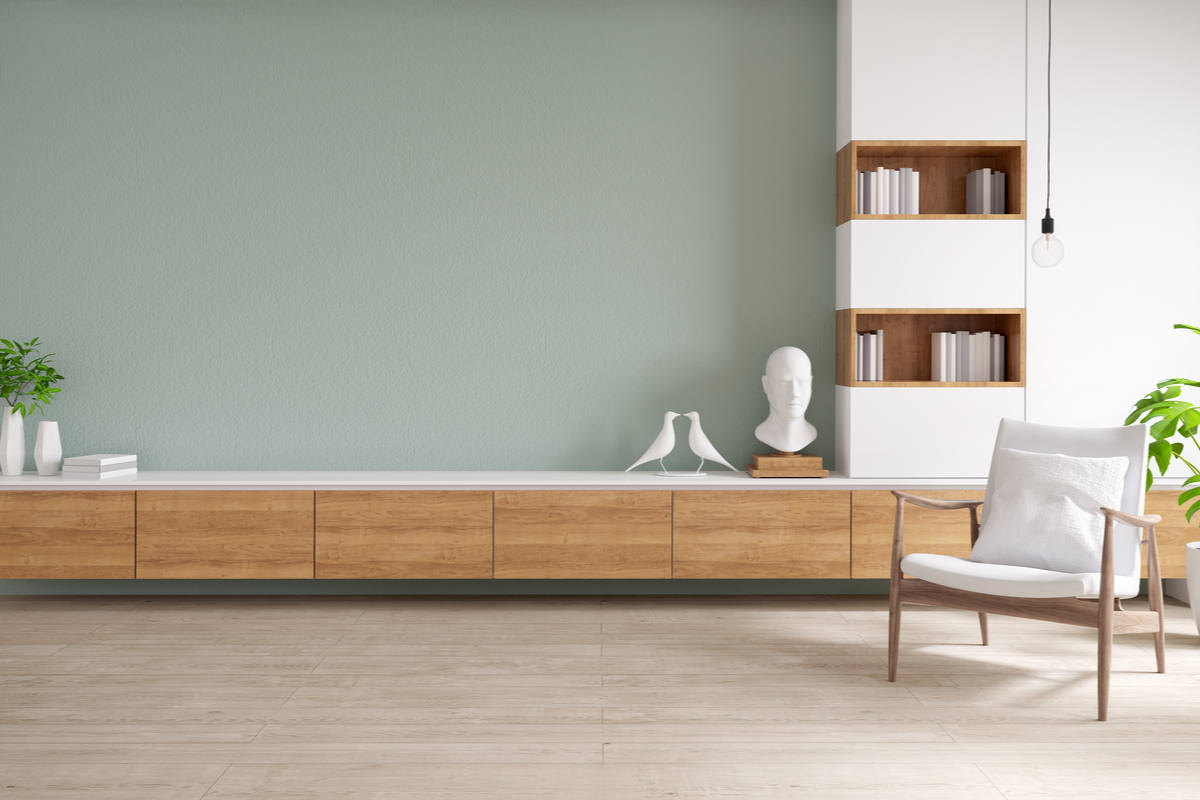 Mobile in color legno e bianco, con pavimenti in legno e parete verde pastello, con sedia con cuscino bianco