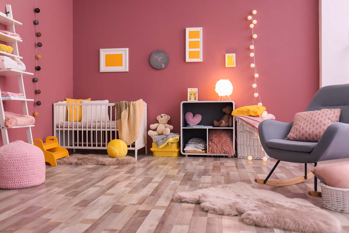 cameretta con pareti rosa acceso, con complementi d'arredo rosa e giallo senape, poltrona grigia, pavimento in parquet 