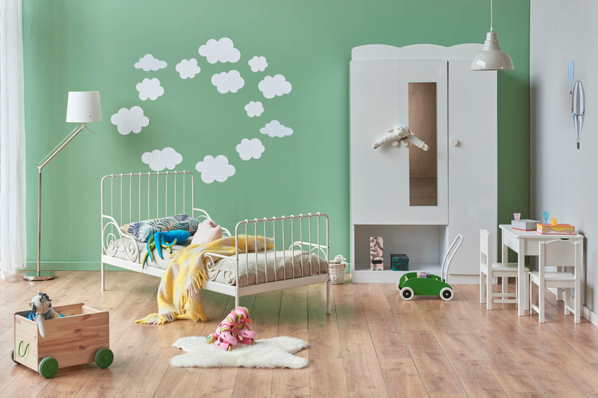 cameretta con parete di colore verde, con nuvolette bianche, letto dal design moderno, armadio bianco e pavimento con parquet