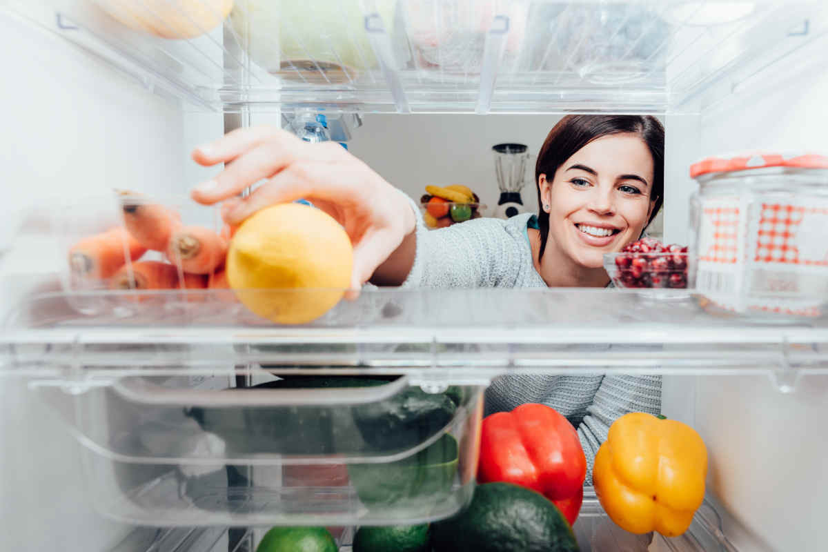 donna apre la porta del frigo per prendere un limone