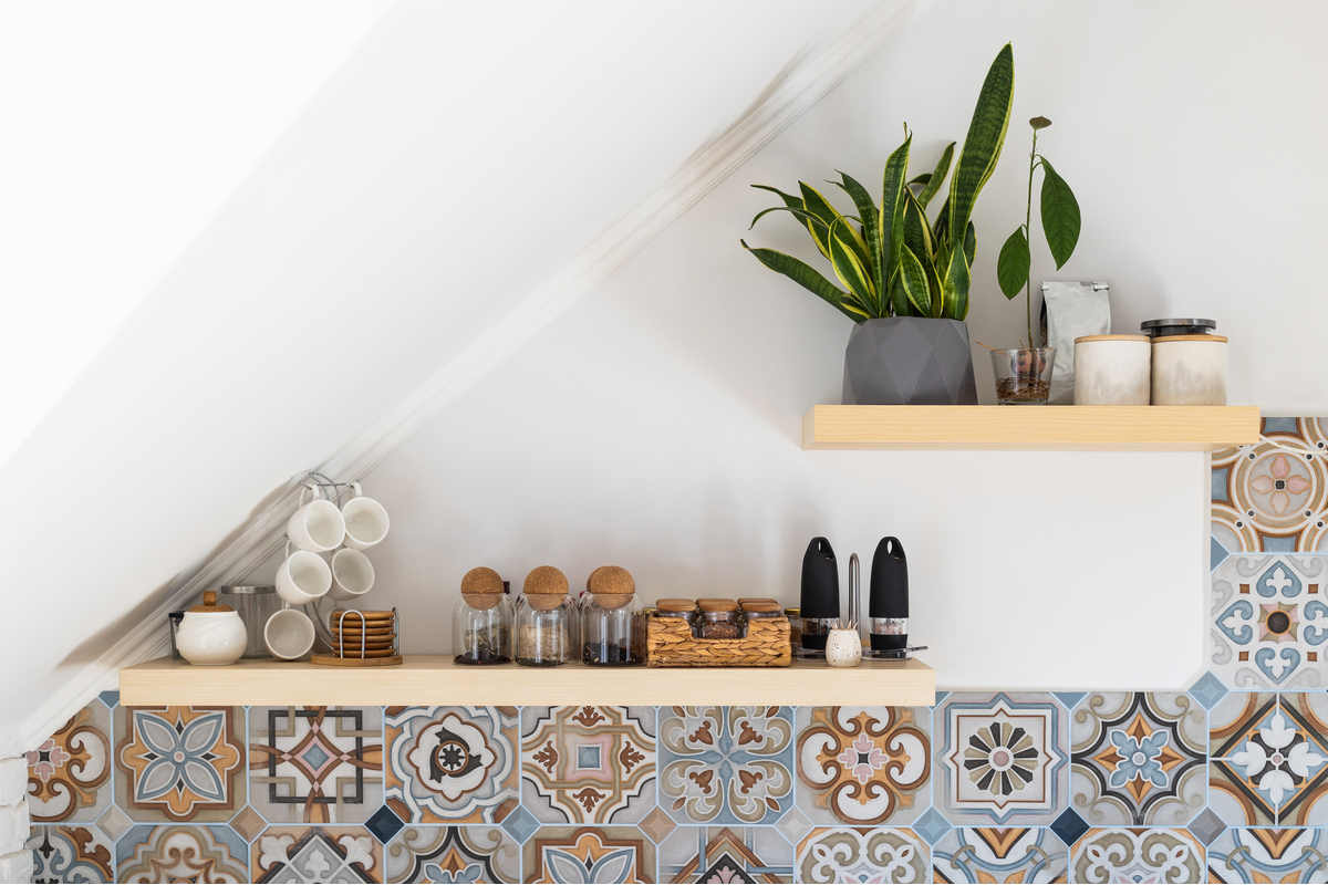 Mensole da cucina e tazze moderne, utensili da cucina, piante in vaso su mensole di legno, su parete chiara e mattonelle in stile turco