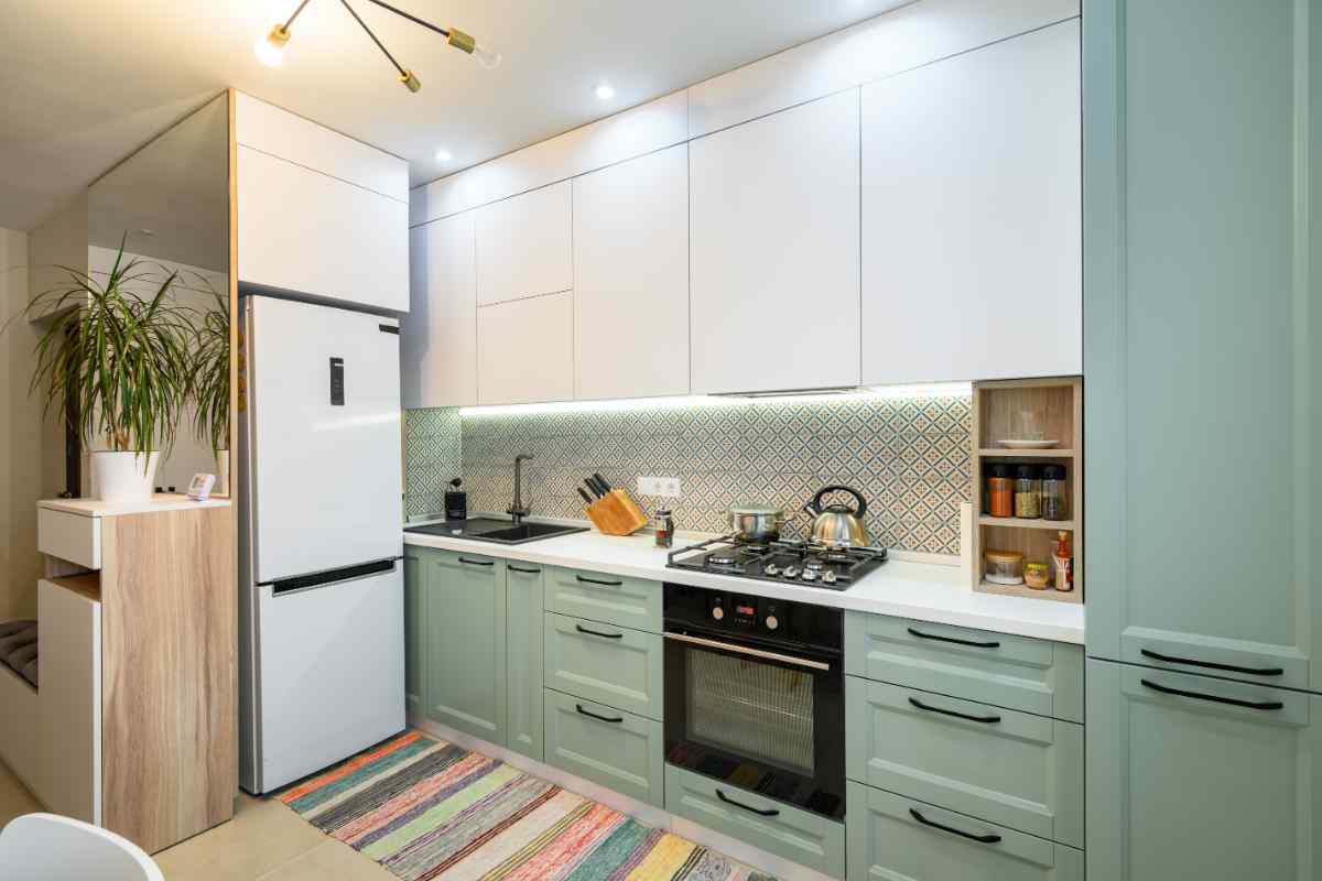 cucina colorata bianca e verde con frigo freestanding e tappeto multicolor