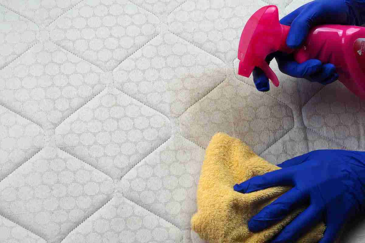 donna disinfetta materassi con spruzzino e panno morbido