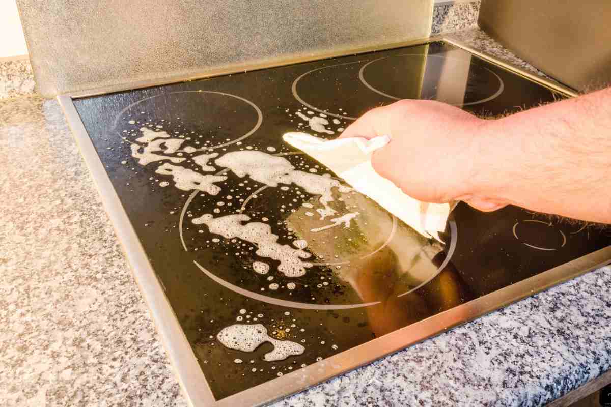 mano toglie macchie dal piano a induzione