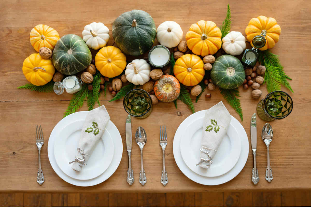Come apparecchiare la tavola per Halloween Piatti, bicchieri da vino, posate vintage su un tavolo di legno. Decorazione della tavola con zucche, noci, candele