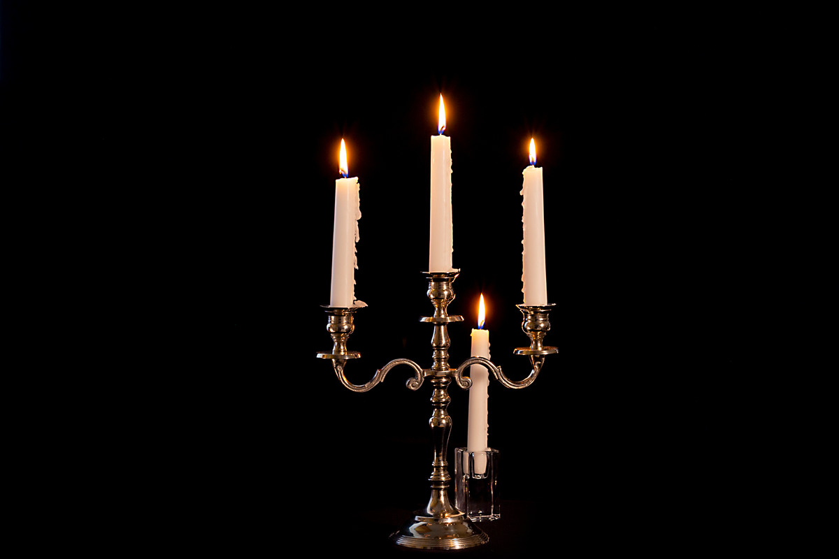 sfondo nero con candelabro a tre braccia e candele accese e una candela accesa