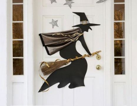 decorazione per halloween su porta bianca con strega di colore nero su una scopa