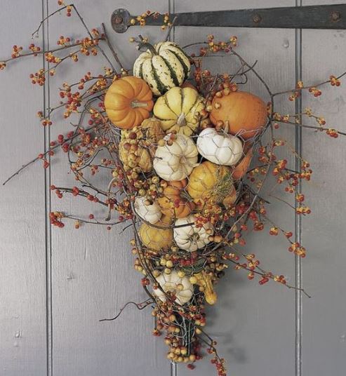 decorazione di halloween a forma di cono con rami secchi e zucche di colore arancio, verde e bianco