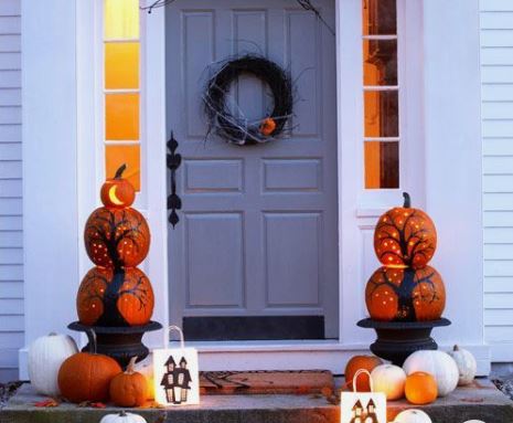 decorazioni per halloween sulla porta d'ingresso con zucche e ghirlanda appesa alla porta