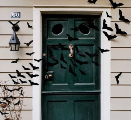 decorazione per halloween con pipistrelli di colore nero su porta d'ingresso di colore verde