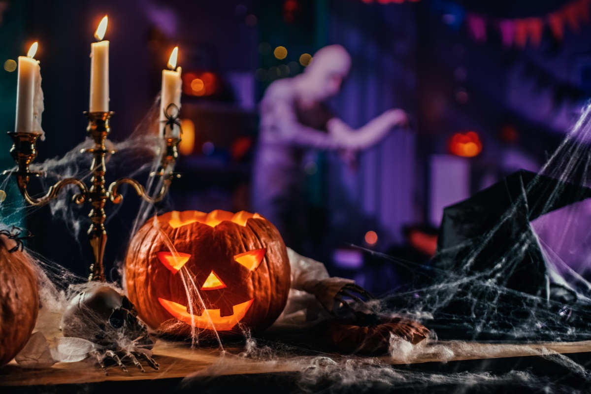 tavolo allestito con candelabro a tre braccia, zucca di halloween, il tutto ricoperto da ragnatele finte