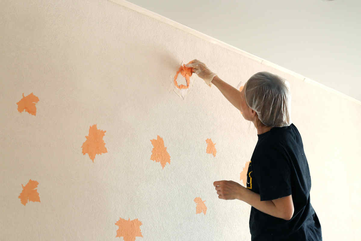 donna applica stencil su parete da decorare