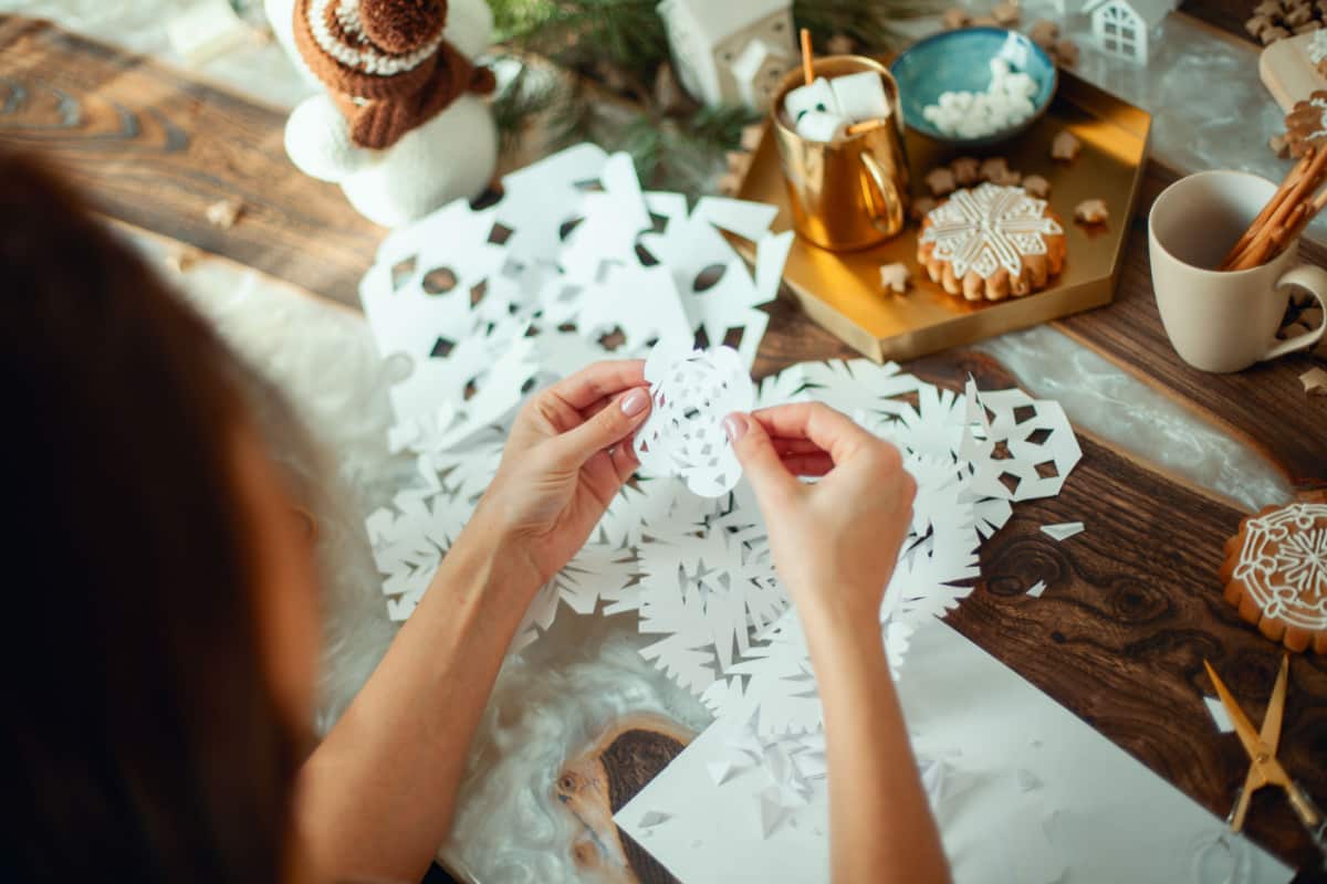 mani di ragazza che creano un centrotavola di carta di colore bianco