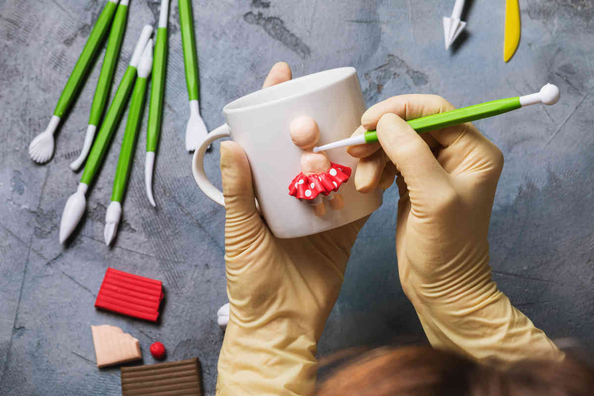 uomo realizza creazioni in fimo su mug