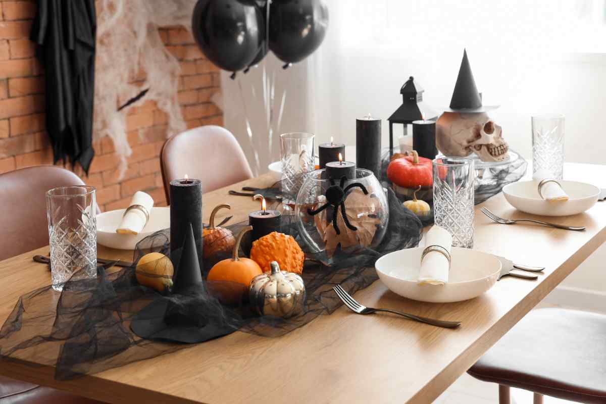 una tavola con al centro un centrotavola di Halloween fai da te con zucche e candele
