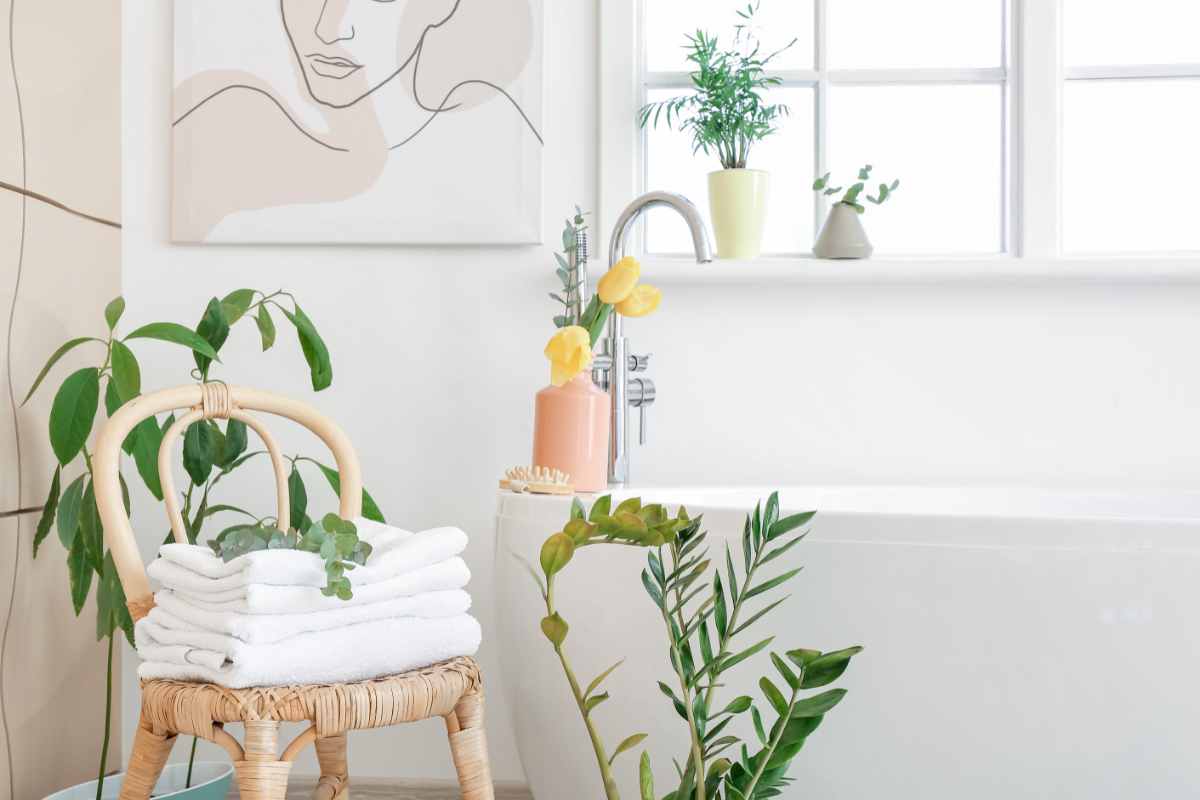 bagno con piante, sedia in rattan e asciugamani