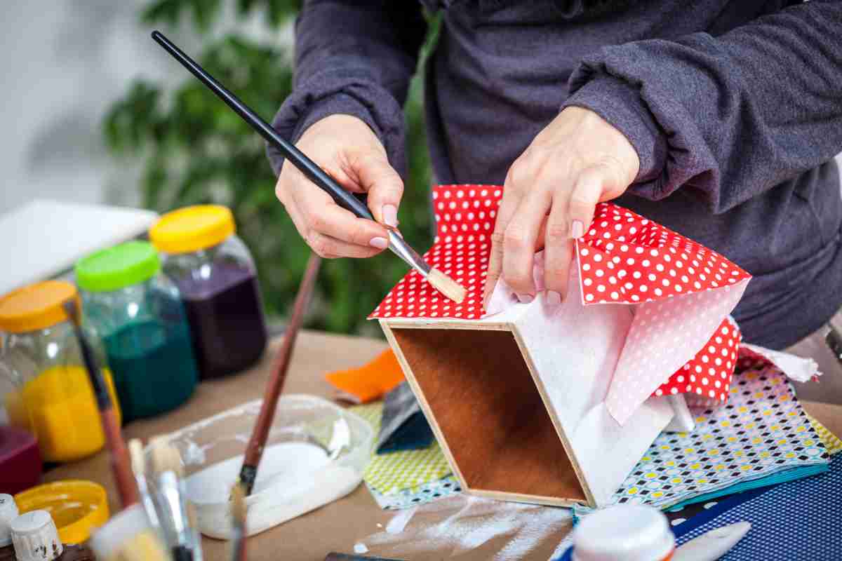 Donna con pennello e carta riveste un cassetto di legno con il decoupage