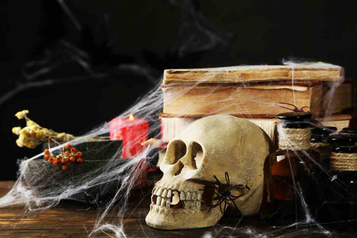 ragnatele finte su libri vecchi, teschio e candele di halloween