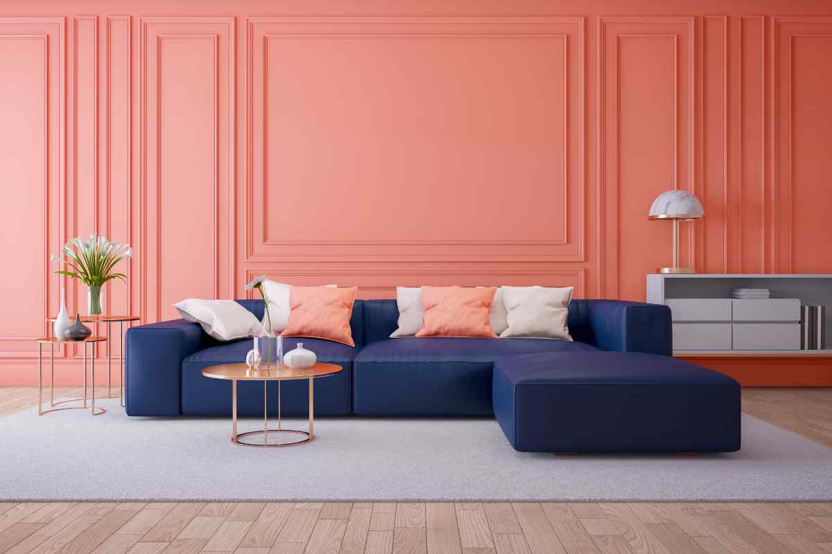 Soggiorno con pareti in boiserie color salmone e divano blu
