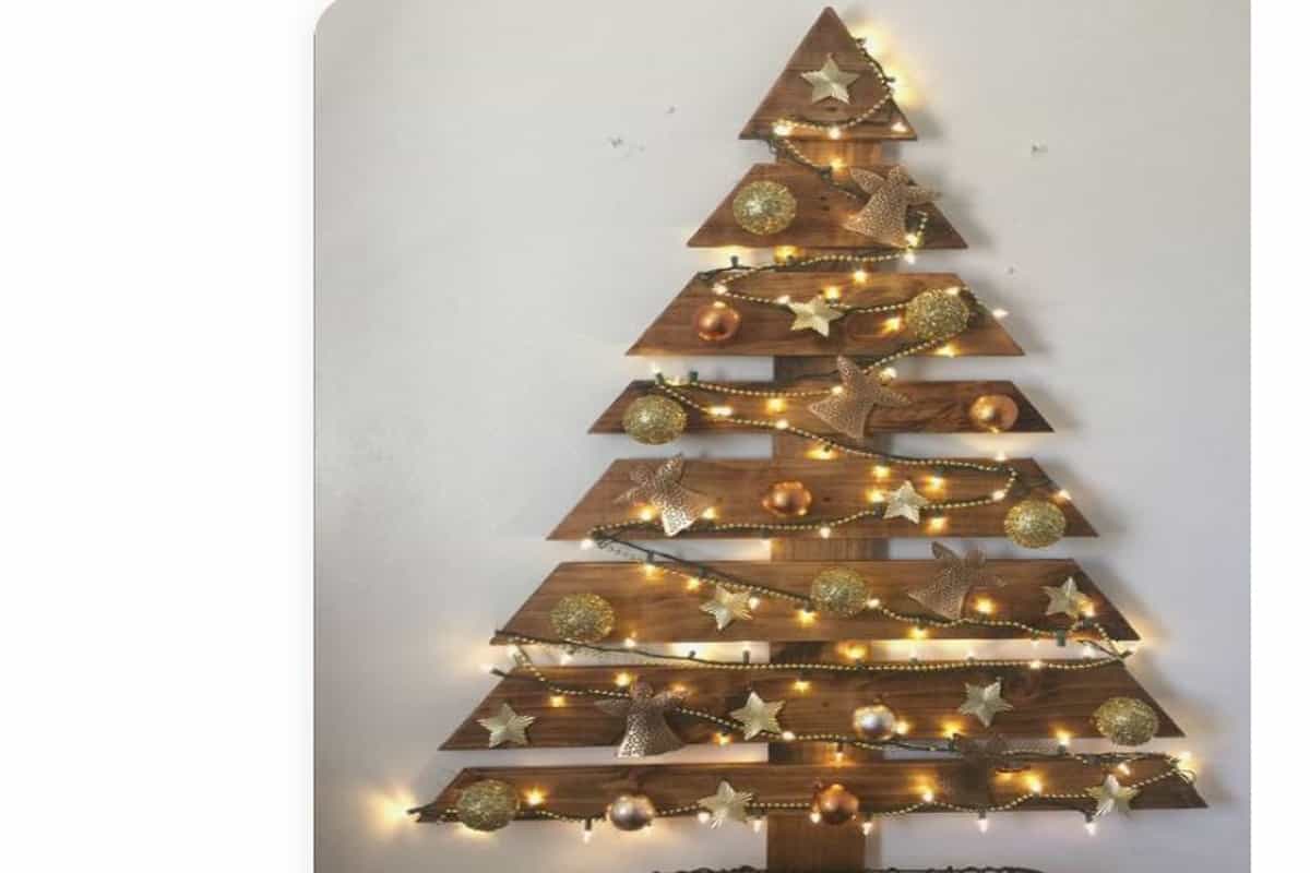 albero di natale con bancale in legno pallet con lucine, su una parete bianca 