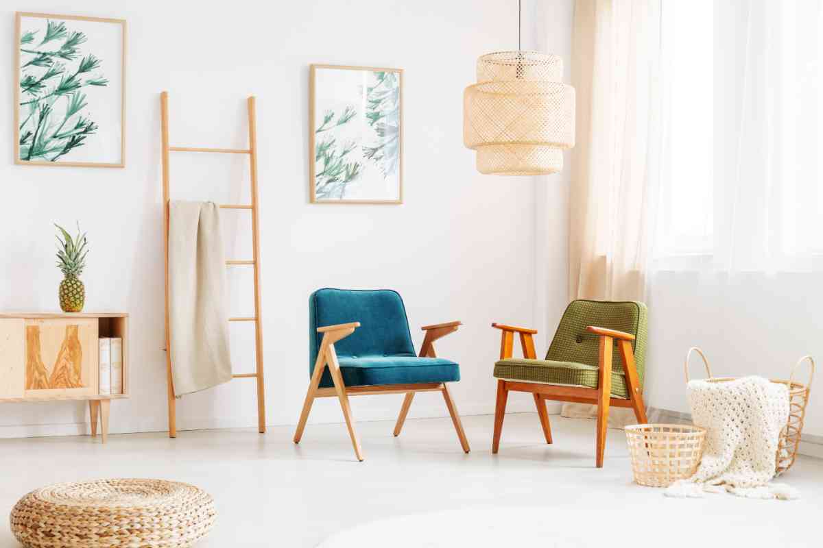 soggiorno con parete bianca, tende alle finestre e poltroncine in legno con rivestimento blu e verde