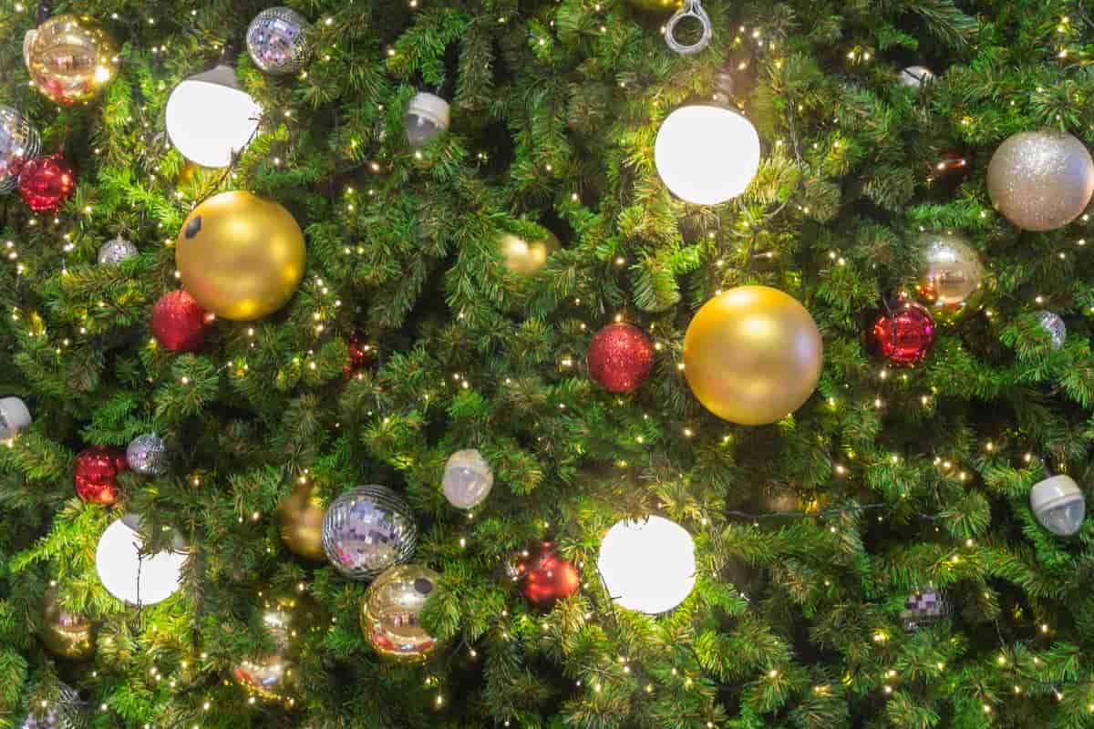 zoom sui rami di un albero di natale decorato con palline grandi, colorate e illuminate