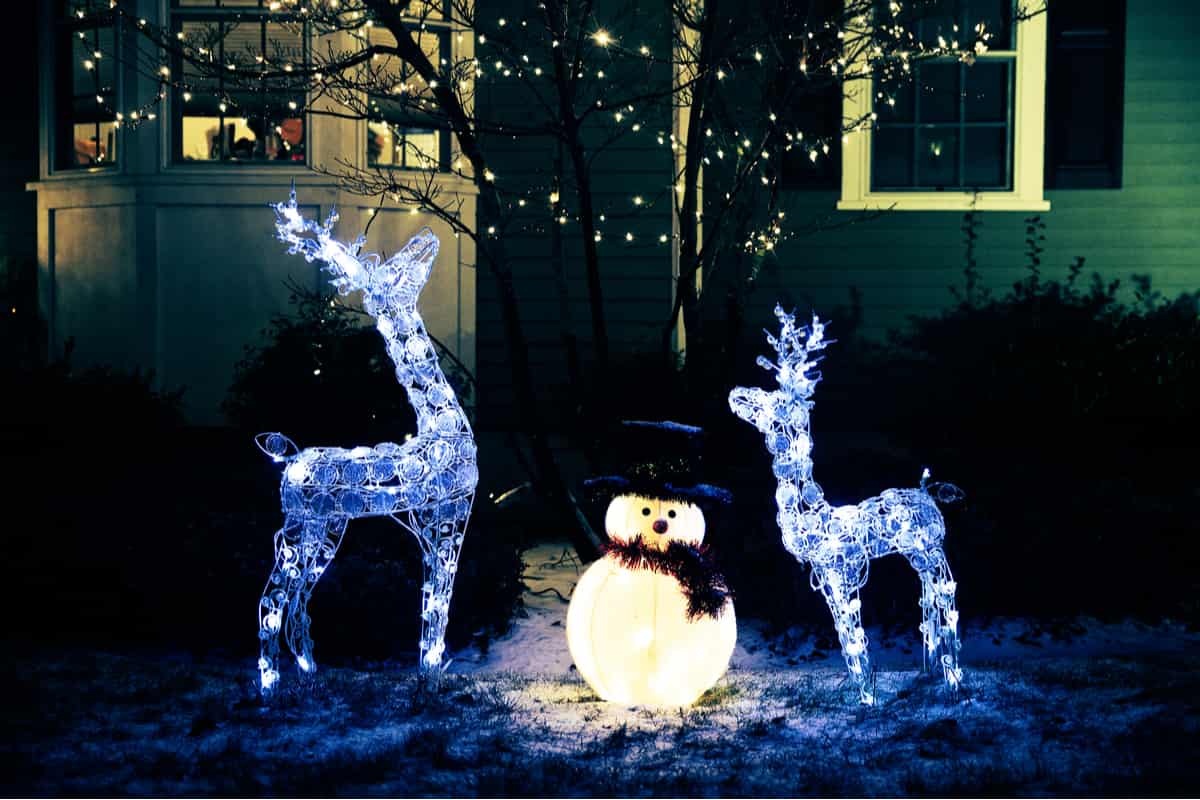 giardino innevato con due renne luminose e un pupazzo di neve illuminato