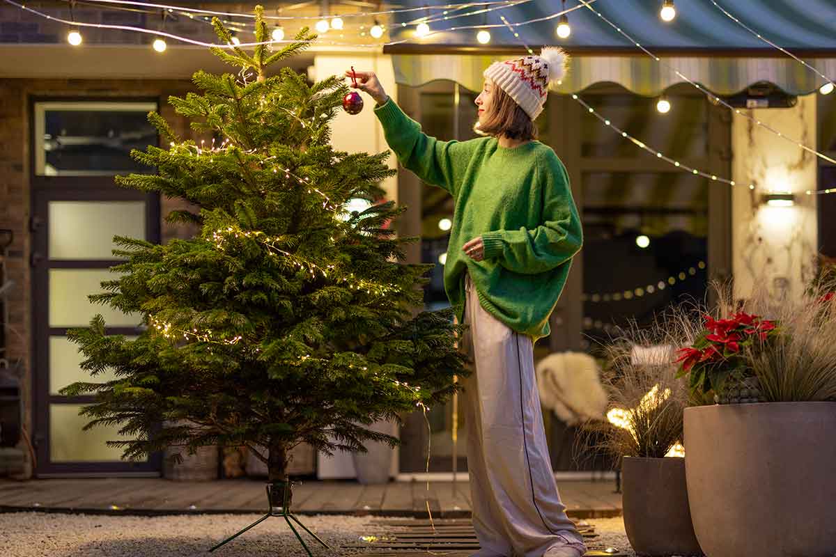 ragazza decora albero natale in giardino