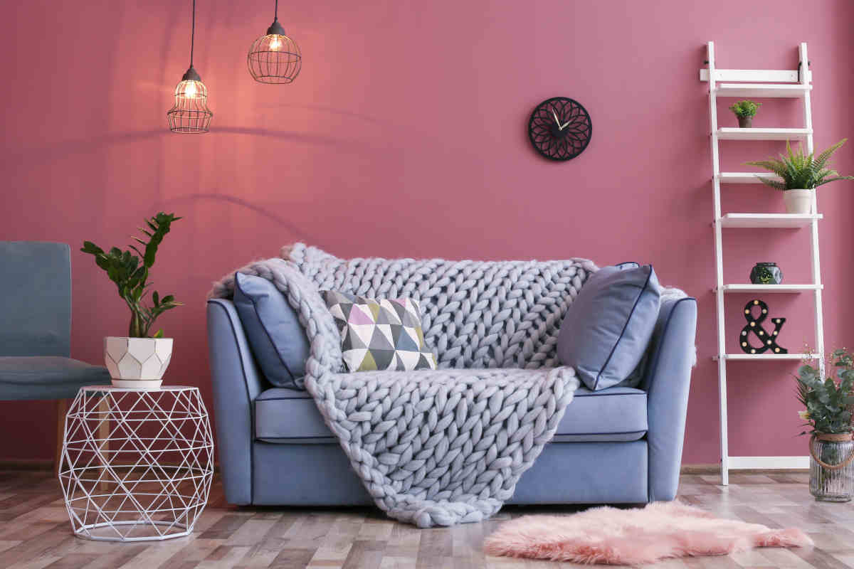 soggiorno con parete rosa e divano lilla