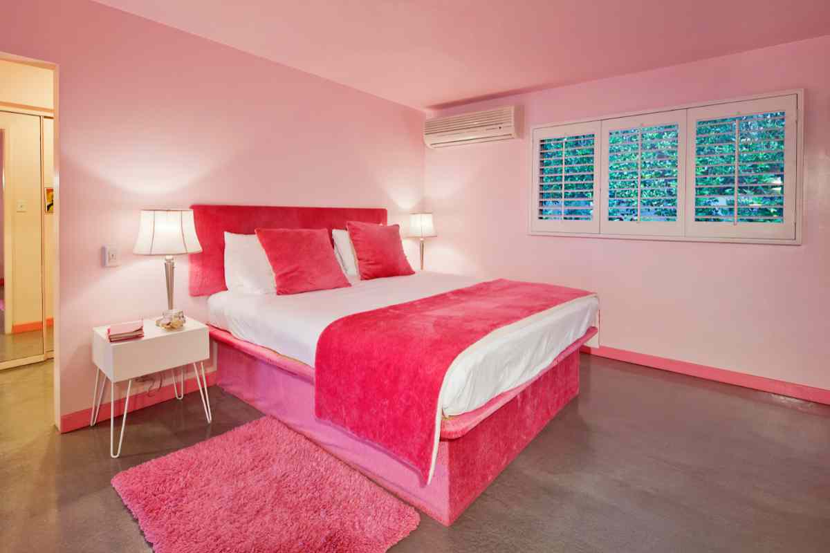 Camera da letto con letto, tappeto e coperta color magenta