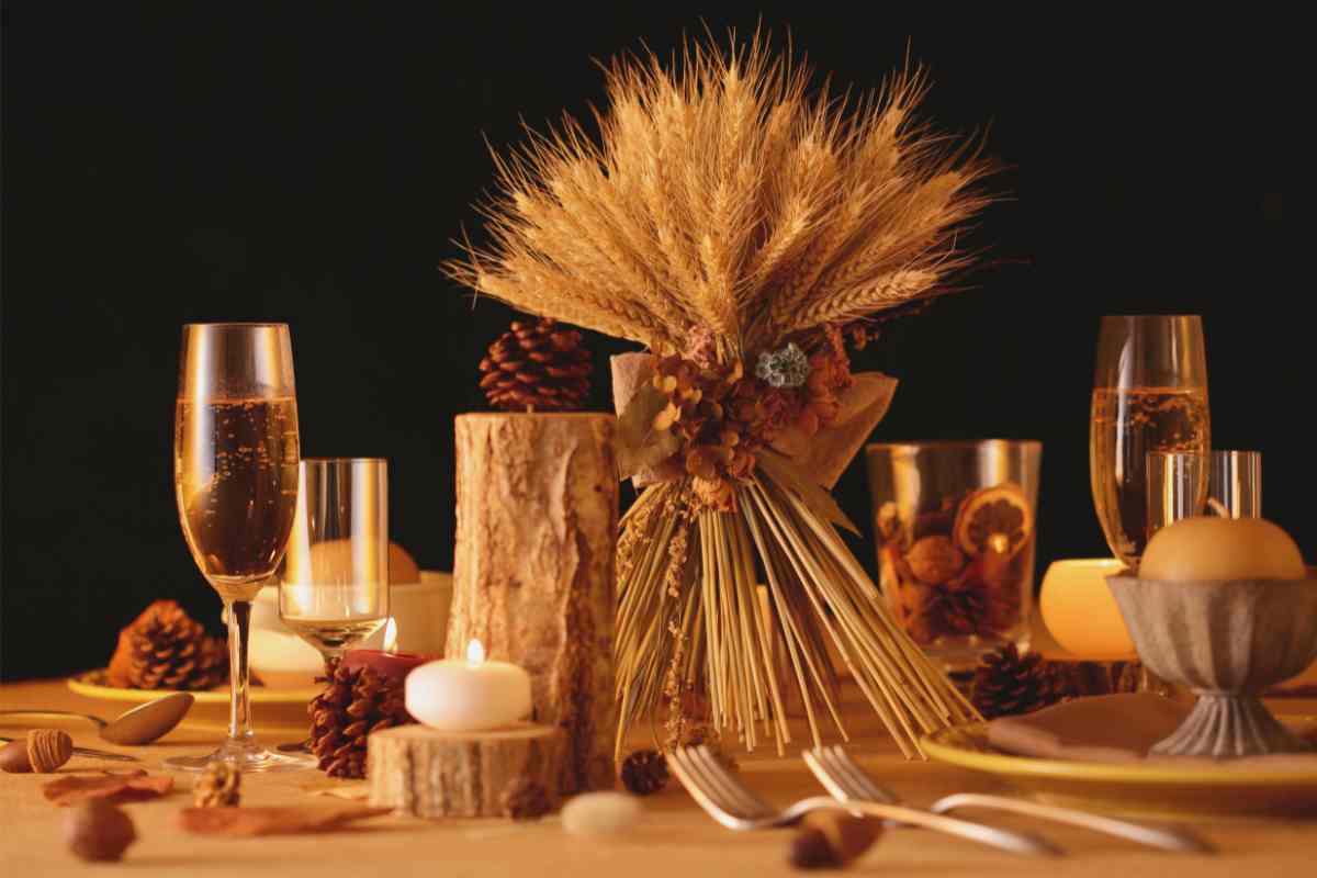 tavola apparecchiata con centrotavola fai da te con spighe di grano, tronchi e candele