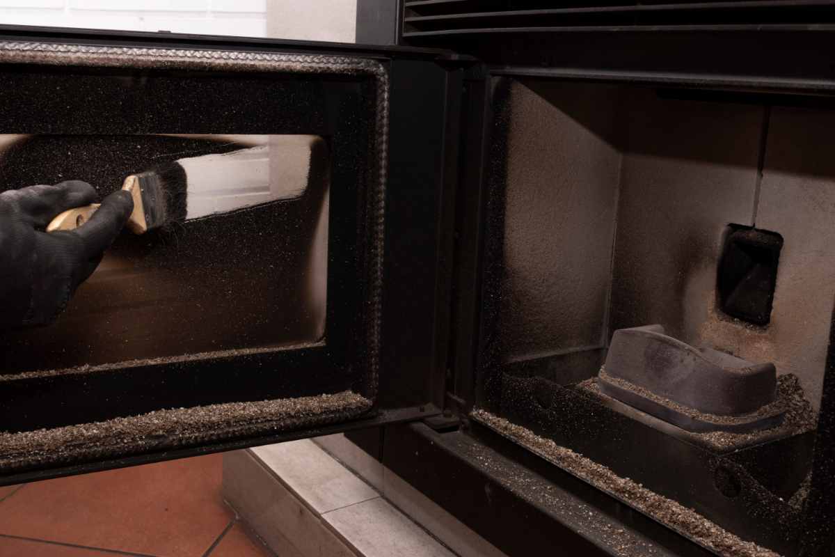 persona pulisce il vetro della stufa a pellet