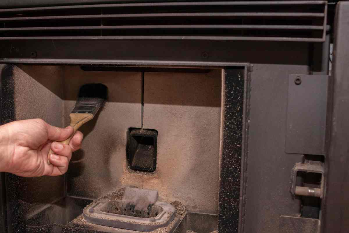 una persona passa il pennello nella stufa a pellet per pulirla