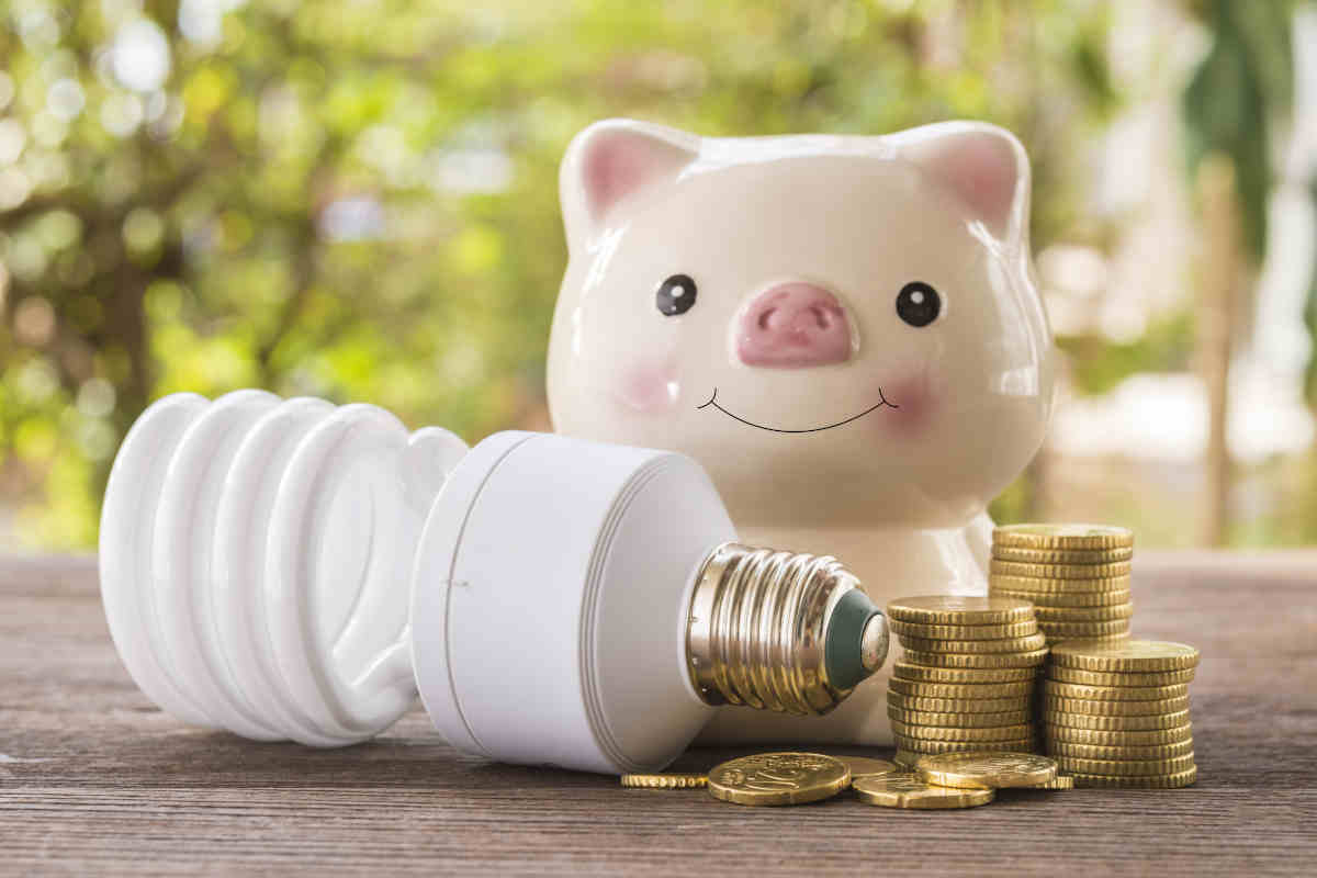 concetto di risparmio energetico, lampadina con monete e salvadanaio