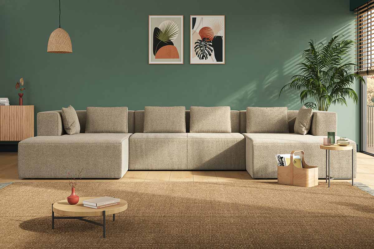 Divano ampio di colore beige con parete verde dietro