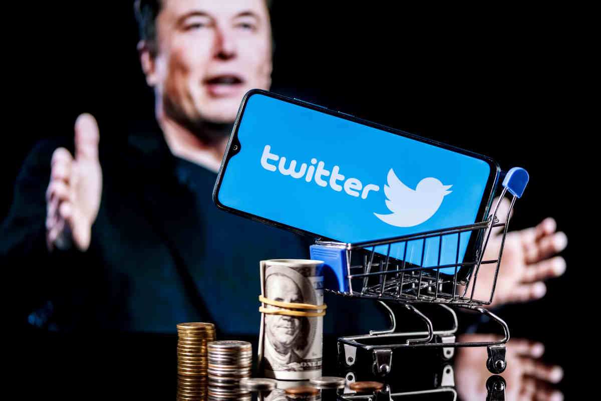 elon musk sullo sfondo e smartphone con logo twitter in primo piano