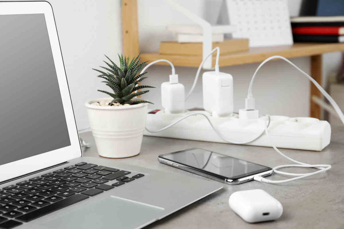 laptop su scrivania con gadget elettrici per risparmiare sulle bollette