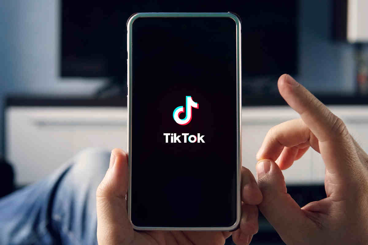 uomo con un mano uno smartphone con logo tiktok