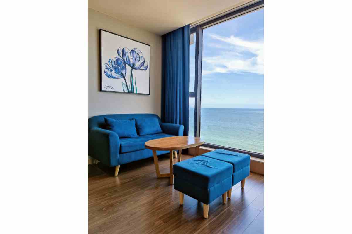abbinamento di un quadro con fiori blu in soggiorno con salottino, pouf e tende blu 