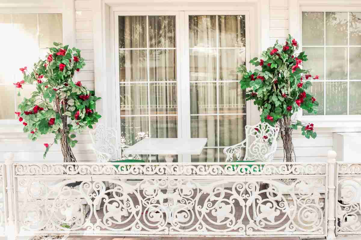 balcone con arredi bianchi in ferro e piante